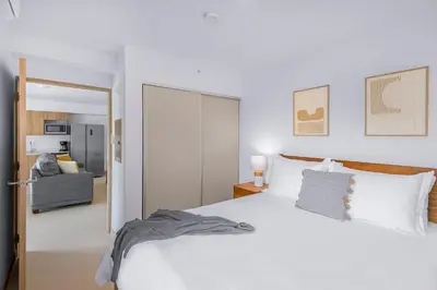 a bedroom with a white bed and a living room at Upstay - New Condo in Jaco - 5 mins from Beach in Jacó