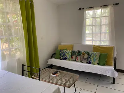 a living room with a couch with green curtains at Manzu in Santa Cruz