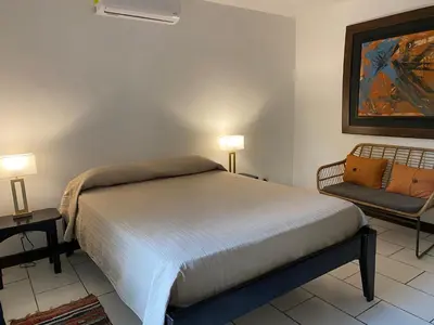 a bedroom with a bed with two lamps and a chair at Manzu in Santa Cruz