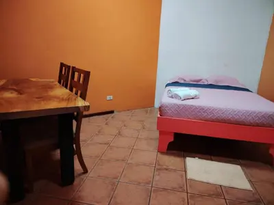a small bedroom with a bed and a table at Hospedaje Papalotes in Quepos