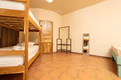 a bedroom with two bunk beds and a tiled floor at Hospedaje Papalotes in Quepos
