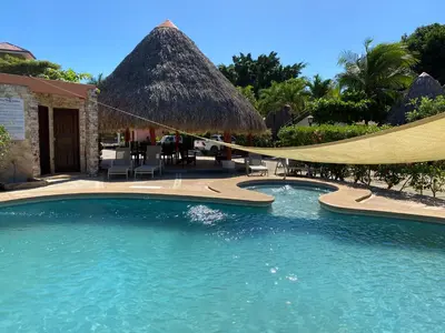a swimming pool with a thatched umbrella and chairs at 2bd 2bth Vacation villa in Tamarindo, Costa Rica in Tamarindo