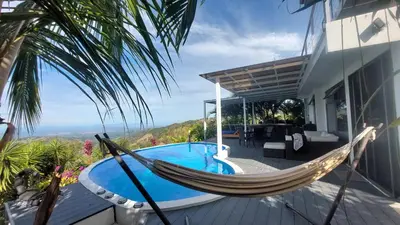 a hammock on the deck of a house with a pool at Palco Pacifico at The Retreat in Atenas