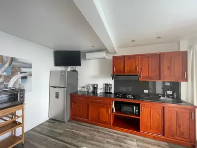 a kitchen with wooden cabinets and a stainless steel refrigerator at Palco Pacifico at The Retreat in Atenas