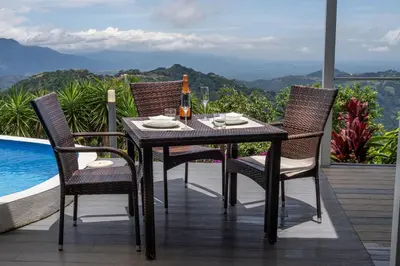 a dining table and chairs on a balcony with a view at Palco Pacifico at The Retreat in Atenas