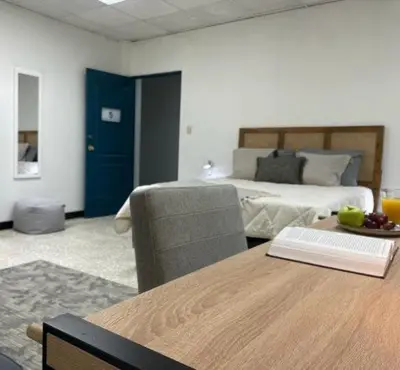 a living room with a bed and a table with a book at San Jose Downtown Suites in San José