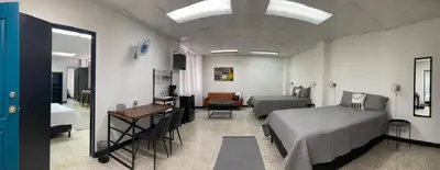 a room with two beds and a desk and a bedroom at San Jose Downtown Suites in San José