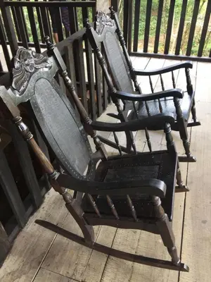 a pair of rocking chairs sitting on a porch at La Cueva del Sapo Experience a genuine countryside farm wooden house in Horquetas