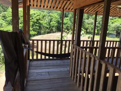 a porch of a cabin with a hammock on it at La Cueva del Sapo Experience a genuine countryside farm wooden house in Horquetas