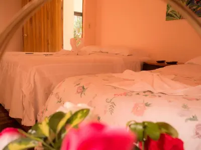 a bedroom with two beds with white sheets and pink flowers at Monte Los Lirios Lodge in Monteverde Costa Rica