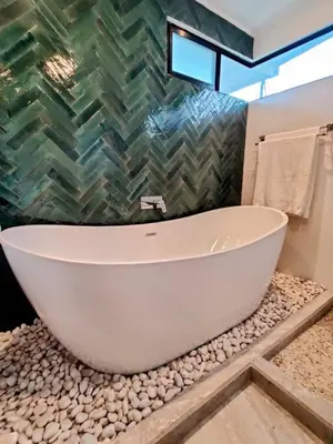 a bathroom with a large white bath tub on a pebble counter at CASA TROPICAL-3 bdrm w private pool Close to beach in Esterillos