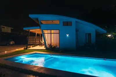 a swimming pool in front of a house at night at TAMANDUA HOMES el centro de Uvita in Uvita