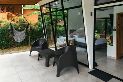a room with chairs and a hammock and a bedroom at TAMANDUA HOMES el centro de Uvita in Uvita