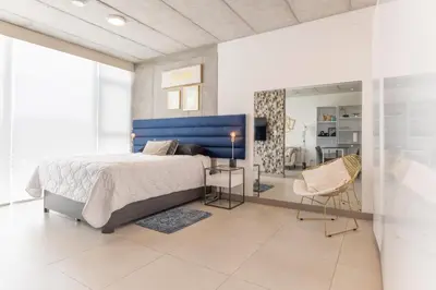 a bedroom with a large bed and a blue headboard at Cityscape iFreses, 20th floor! AC, TV and Pool in Guayabos