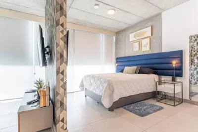 a bedroom with a bed and a blue headboard at Cityscape iFreses, 20th floor! AC, TV and Pool in Guayabos