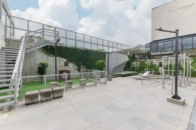 an outdoor patio with a building with a green hedge at Cityscape iFreses, 20th floor! AC, TV and Pool in Guayabos