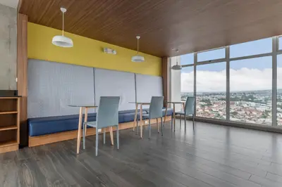 a dining room with tables and chairs and windows at Vista Verde iFreses, 2nd floor! AC, TV and Pool in Guayabos