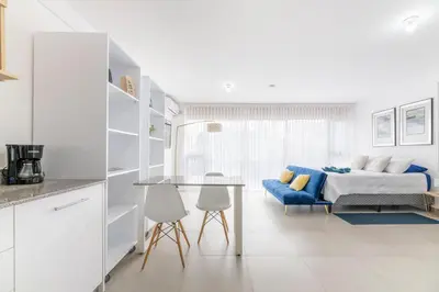 a white bedroom with a bed and a table at Urban Vista iFreses, 2nd floor! AC, TV and Pool in Guayabos