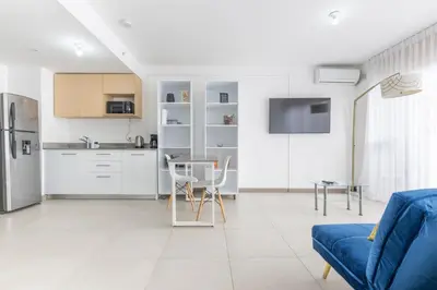a living room with a blue couch and a kitchen at Urban Vista iFreses, 2nd floor! AC, TV and Pool in Guayabos