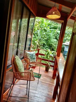 a screened in porch with chairs and a table at Cabaña Luna Arenal in Fortuna