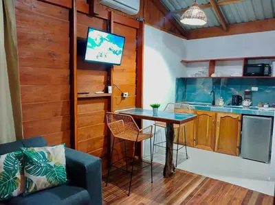 a living room with a table and a kitchen at Cabaña Luna Arenal in Fortuna