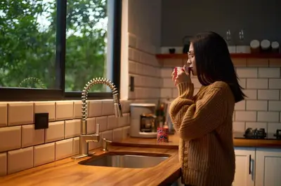 a woman drinking from a cup in a kitchen at Villa Natura in Bajos del Toro