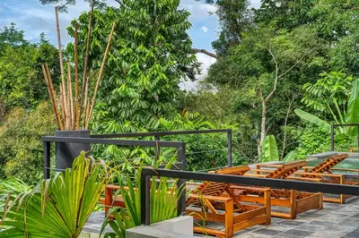 a patio with wooden chairs and a tree at Bali Villa Jungle Paradise - Uvita in Uvita