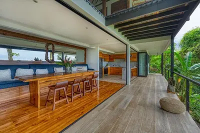 an outdoor kitchen with a large wooden bar on a deck at Bali Villa Jungle Paradise - Uvita in Uvita