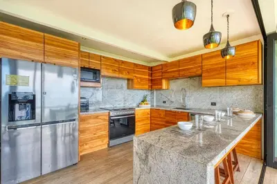 a kitchen with wooden cabinets and a stainless steel refrigerator at Bali Villa Jungle Paradise - Uvita in Uvita