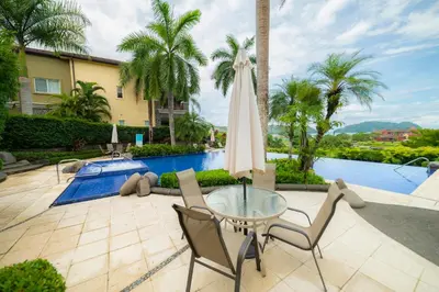 a patio with a glass table and chairs and a pool at Vista Bahia 1G 3 bdr Ocean View in Los Suenos in Herradura