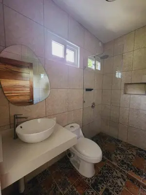 a bathroom with a sink and a toilet and a mirror at Alma Del Bosque Hotel in Tortuguero