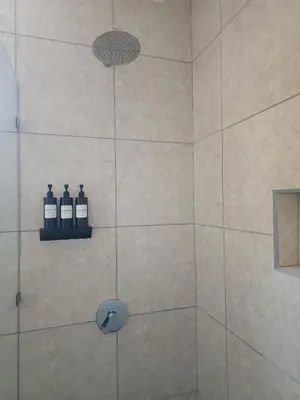 a bathroom with a shower with two bottles of soap at Alma Del Bosque Hotel in Tortuguero