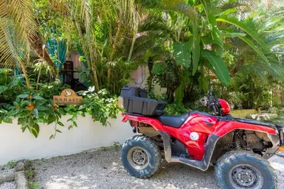 a red atv parked next to a wall with plants at Namaste Beach Bungalow 1 BDR Loft 4 Min to Beach in Nosara