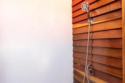 a shower with a hose attached to a wooden wall at Namaste Beach Bungalow 1 BDR Loft 4 Min to Beach in Nosara