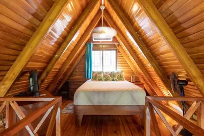 a bedroom in a log cabin with a bed and a window at Namaste Beach Bungalow 1 BDR Loft 4 Min to Beach in Nosara