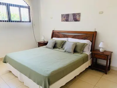 a bed in a bedroom with two night stands and a window at A5 PL Near the beach 1bed 1 office 1 bathroom in Tamarindo