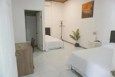 a white room with two beds and a mirror at Cabinas La Sirena in Puntarenas