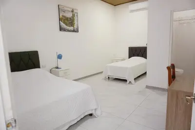 a white room with two beds and a table at Cabinas La Sirena in Puntarenas