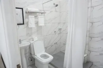 a white bathroom with a toilet and a sink at Cabinas La Sirena in Puntarenas