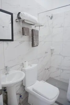 a white bathroom with a toilet and a sink at Cabinas La Sirena in Puntarenas