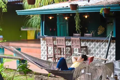 a woman laying in a hammock in front of a house at Turrialba Bed & Breakfast in Turrialba