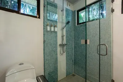 a bathroom with a glass shower with a toilet at Casa Serena - Tranquil Jungle Gem Near the Beach in Uvita