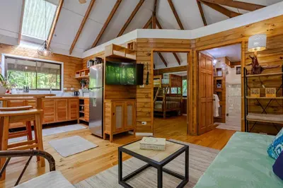 a living room with wood paneling and a kitchen with a tv at Casa Serena - Tranquil Jungle Gem Near the Beach in Uvita