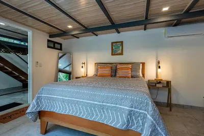 a bedroom with a large bed with orange pillows at Casa Serena - Tranquil Jungle Gem Near the Beach in Uvita