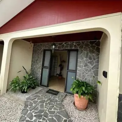 a building with a stone wall and a door with plants at Aurora Retreat Costa Rica in Tilarán