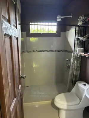 a bathroom with a toilet and a shower with a window at Casita Verde in Uvita