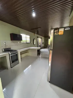 a large room with a kitchen with a refrigerator at Casita Verde in Uvita