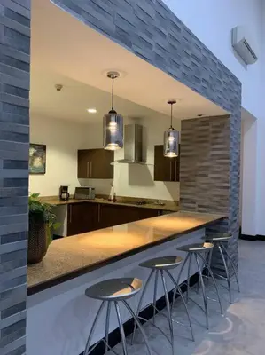 a kitchen with three stools at a bar with a counter at Spacious and Modern Penthouse Condo in Jacó
