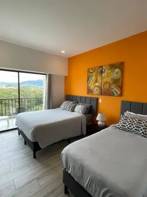 two beds in a room with an orange wall at Spacious and Modern Penthouse Condo in Jacó