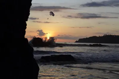 a person flying a kite over the ocean at sunset at BEACH OPEN-FLAT with TERRACE ANALIA in Manuel Antonio